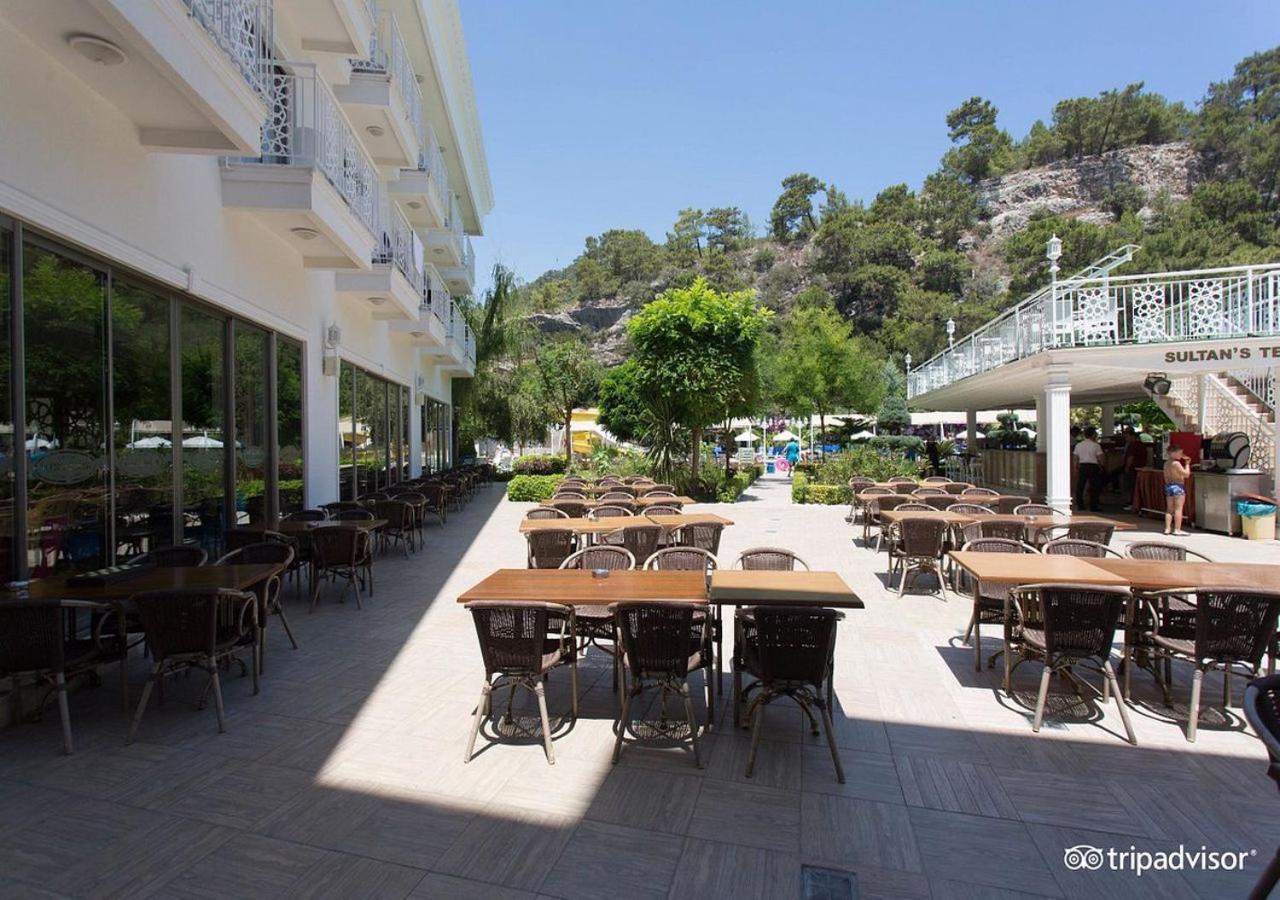 Miramor Hotel & Spa Antalya Exterior foto The photo shows an outdoor dining area, likely at a restaurant or cafe. There are several tables with chairs arranged neatly on the paved ground, and some greenery, such as trees and plants, is visible in the background. The setting appears bright an